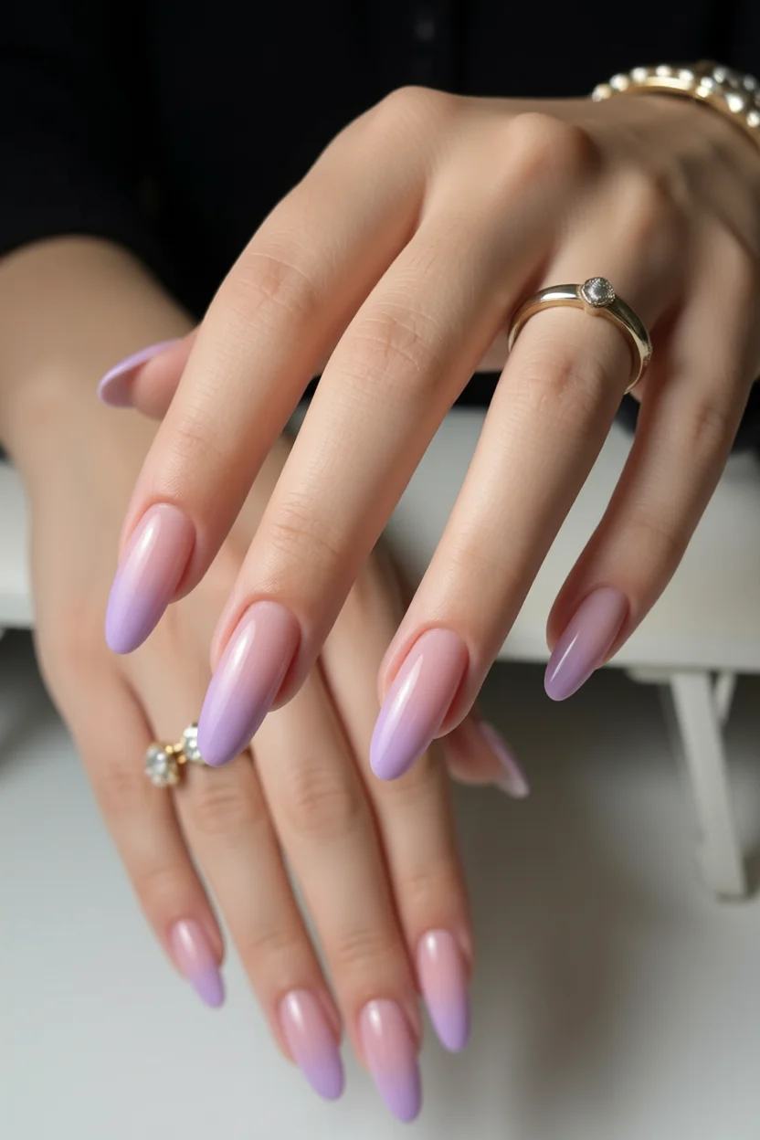 Uñas largas en forma de almendra con efecto ombré lila sobre base nude brillante