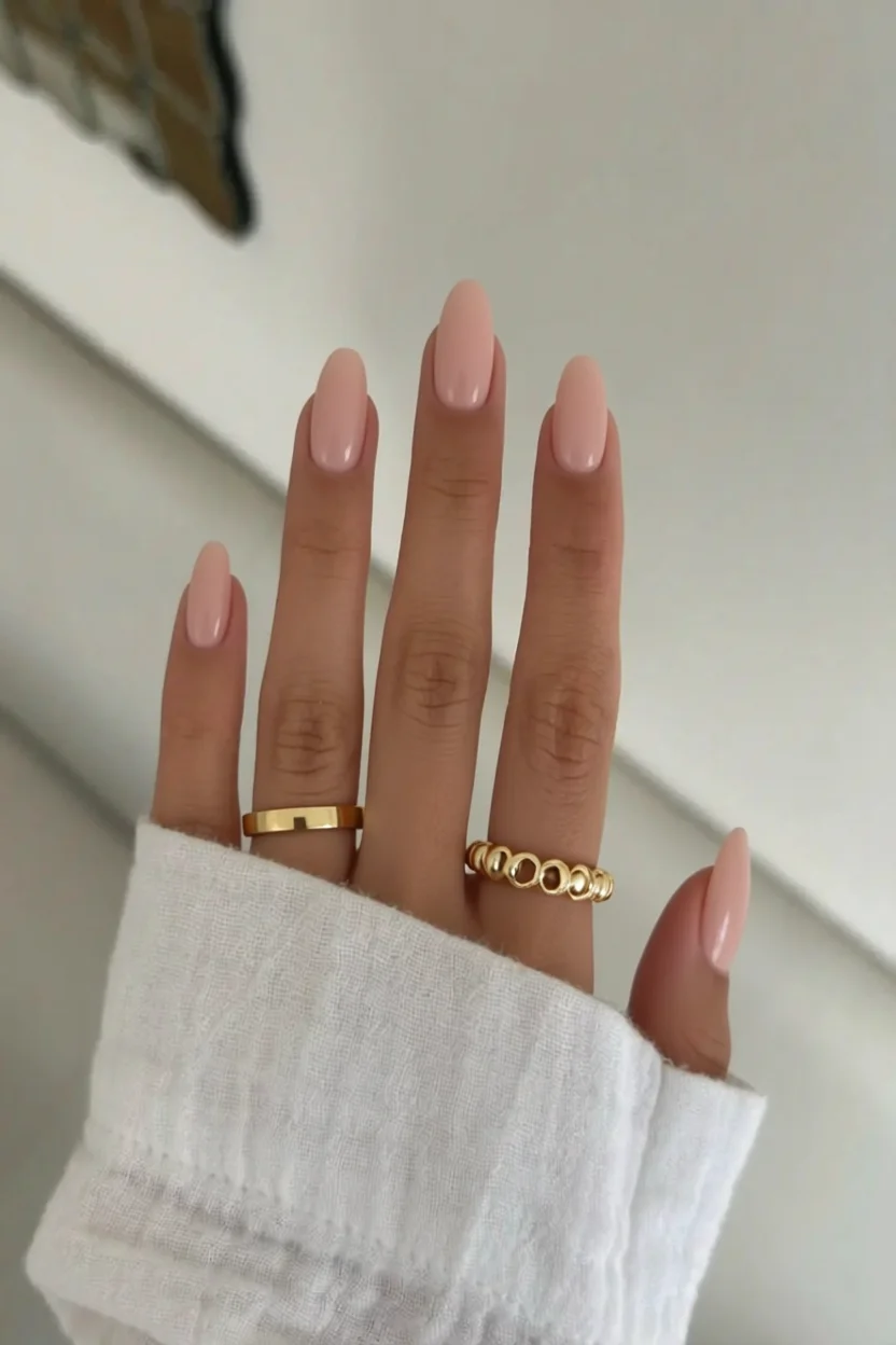 Mano con uñas ovaladas esmaltadas en color nude con brillo intenso