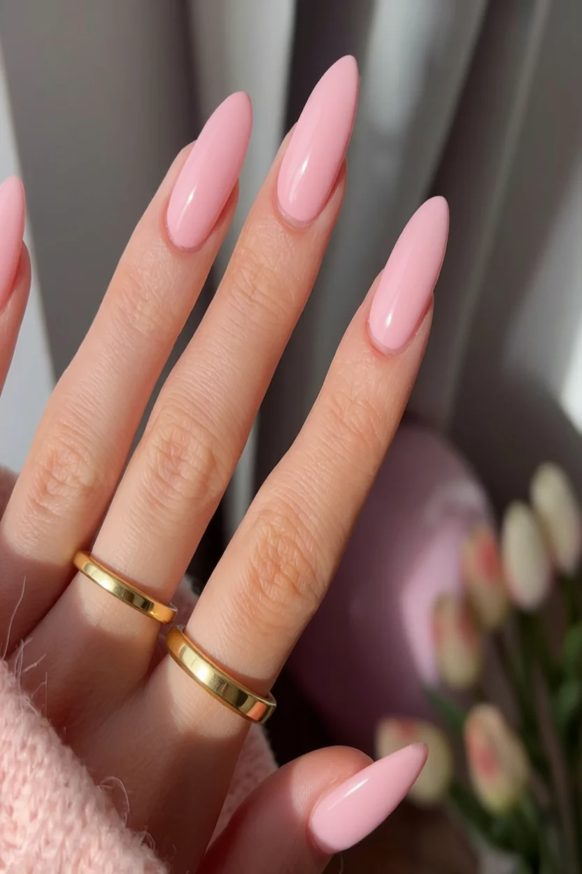 Uñas ovaladas largas esmaltadas en rosa sólido brillante con anillos dorados