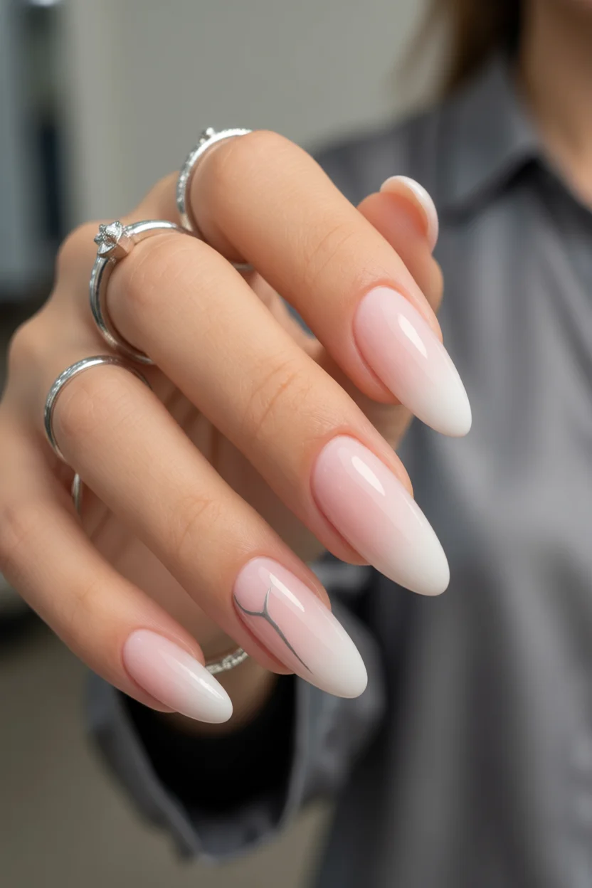 Mano con uñas largas en forma de almendra y diseño degradado en tonos rosa y blanco