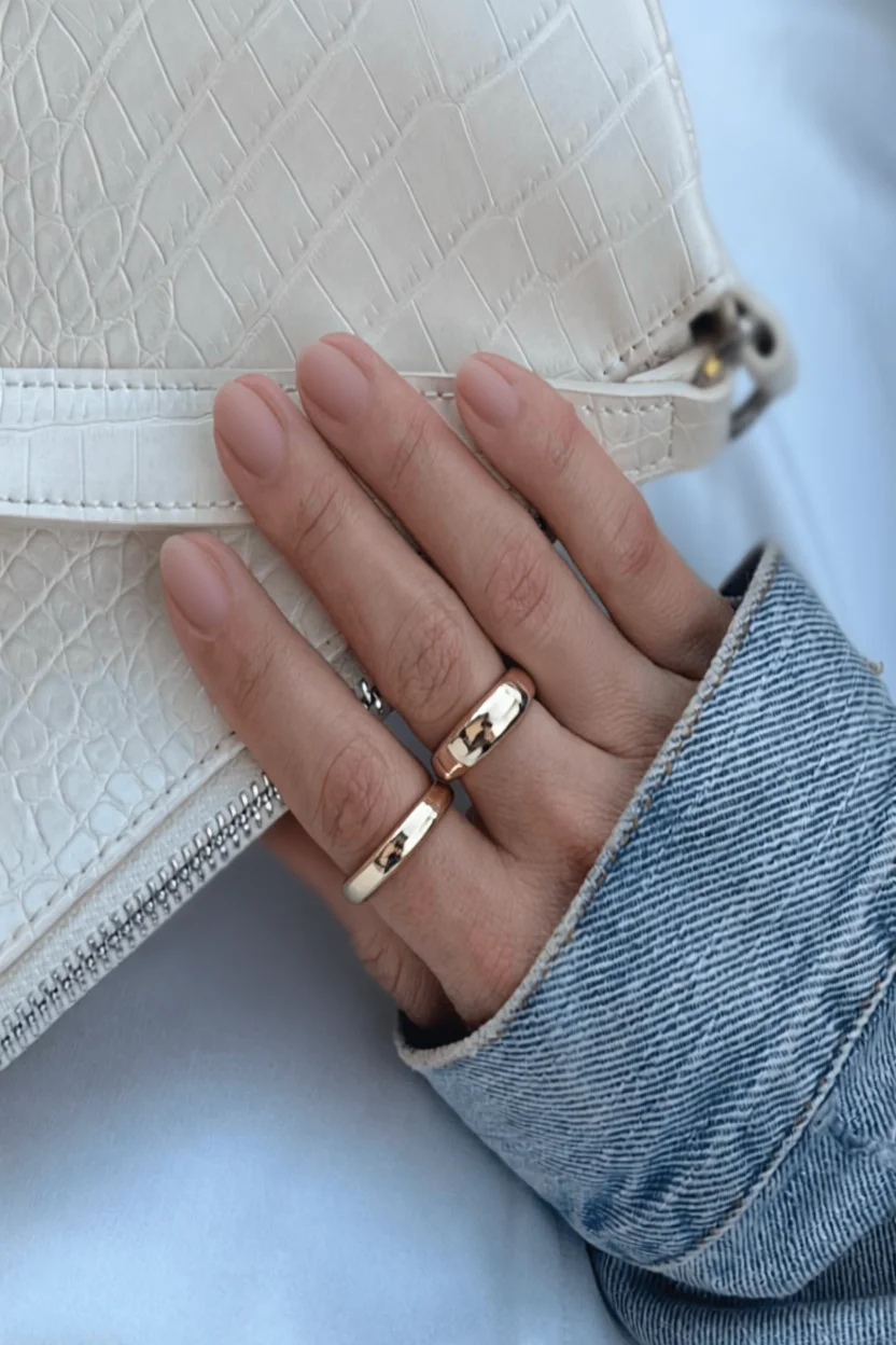 Mano con uñas cortas naturales sin esmalte sosteniendo bolso blanco