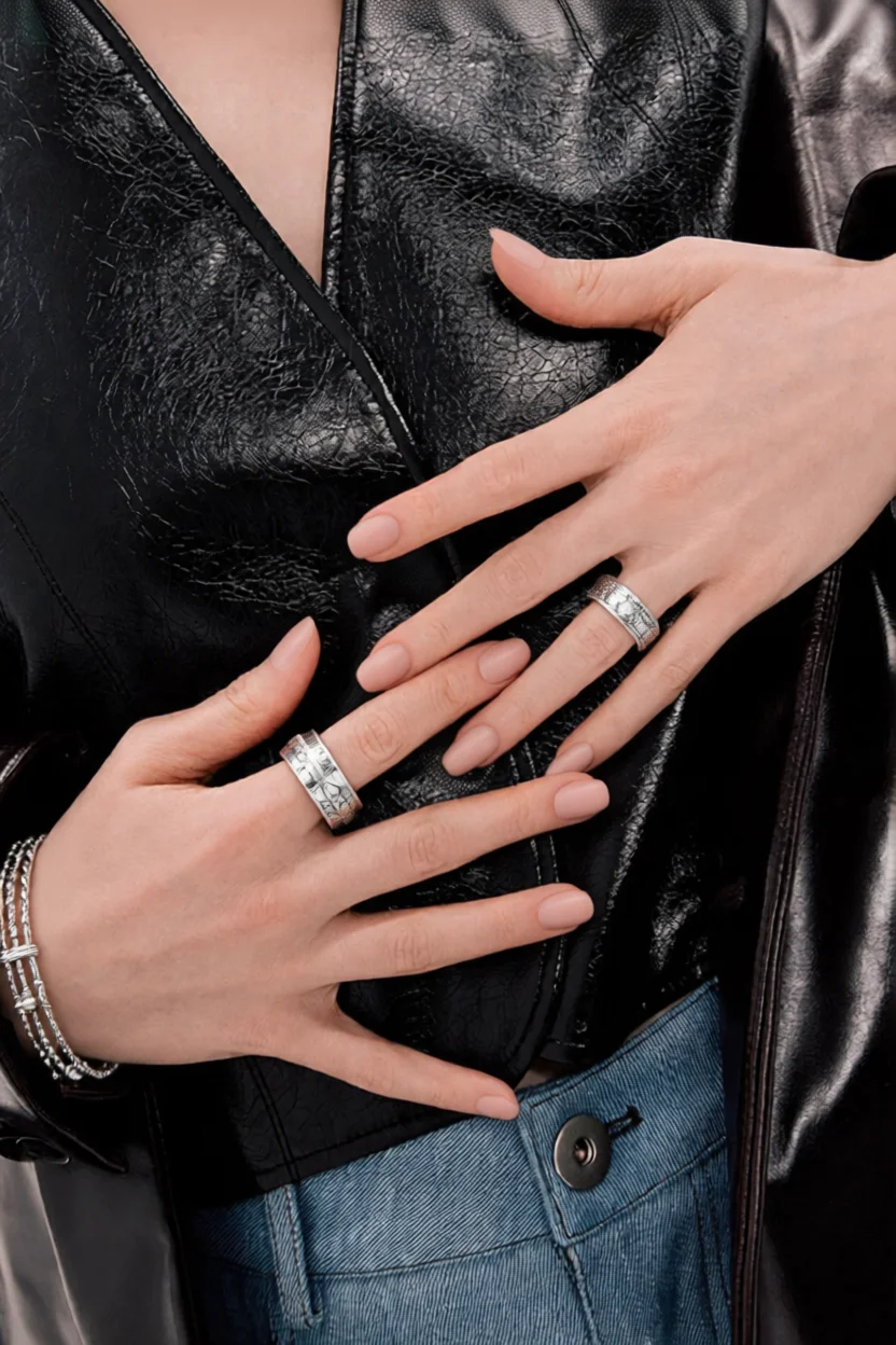 Manos con uñas largas en forma almendrada pintadas de nude y anillos plateados