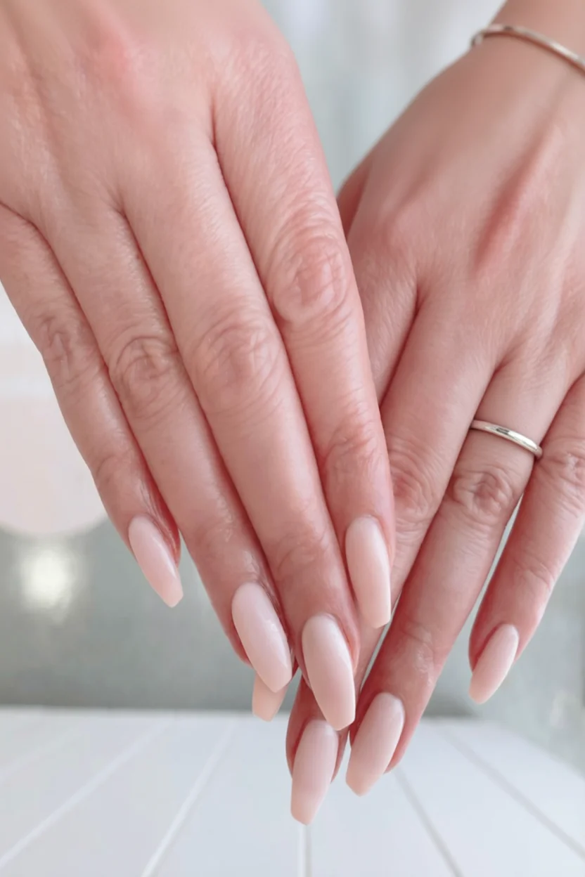 Manos con uñas largas en forma almendra pintadas de color nude brillante