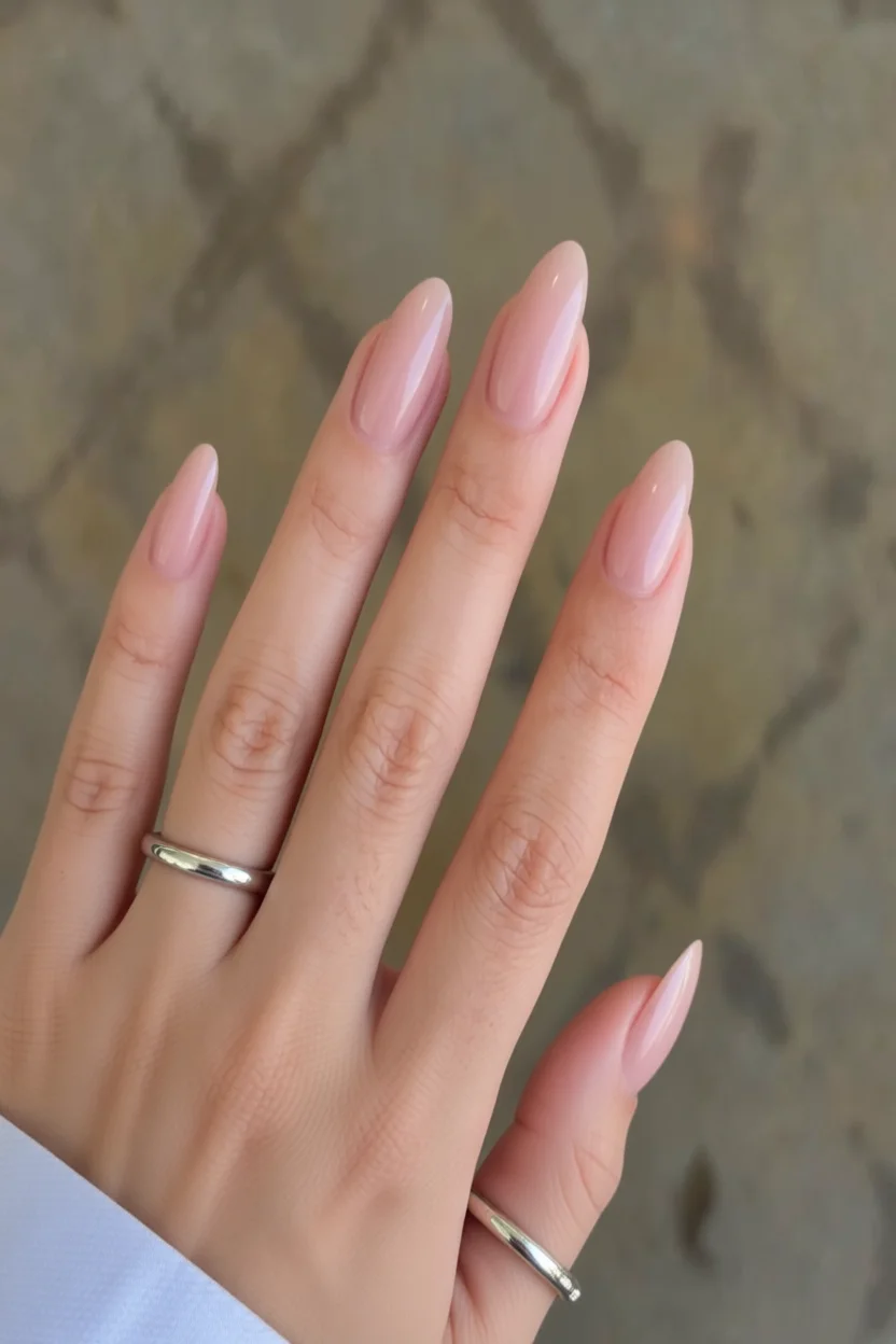 Mano con uñas largas en forma de almendra y esmalte nude brillante