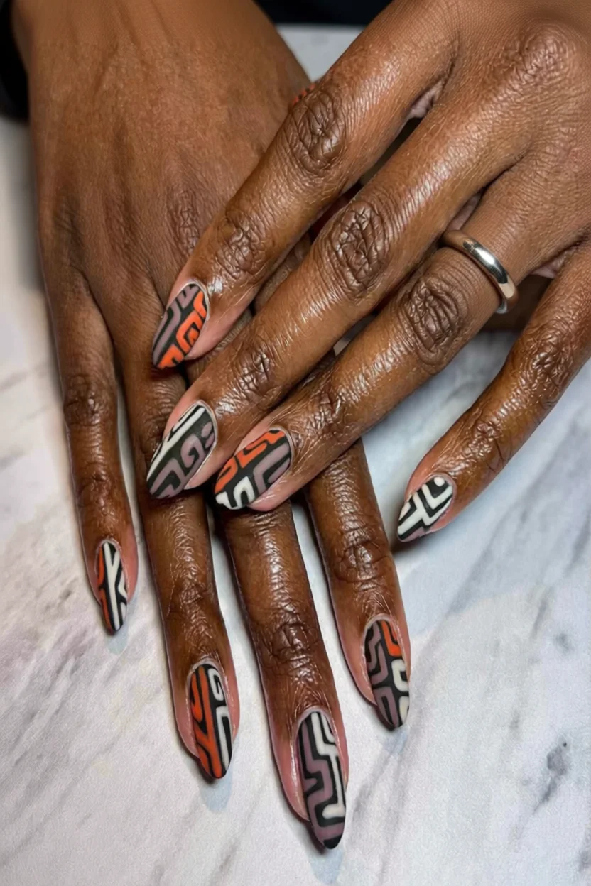 Uñas largas geométricas en tonos naranja, negro, blanco y gris