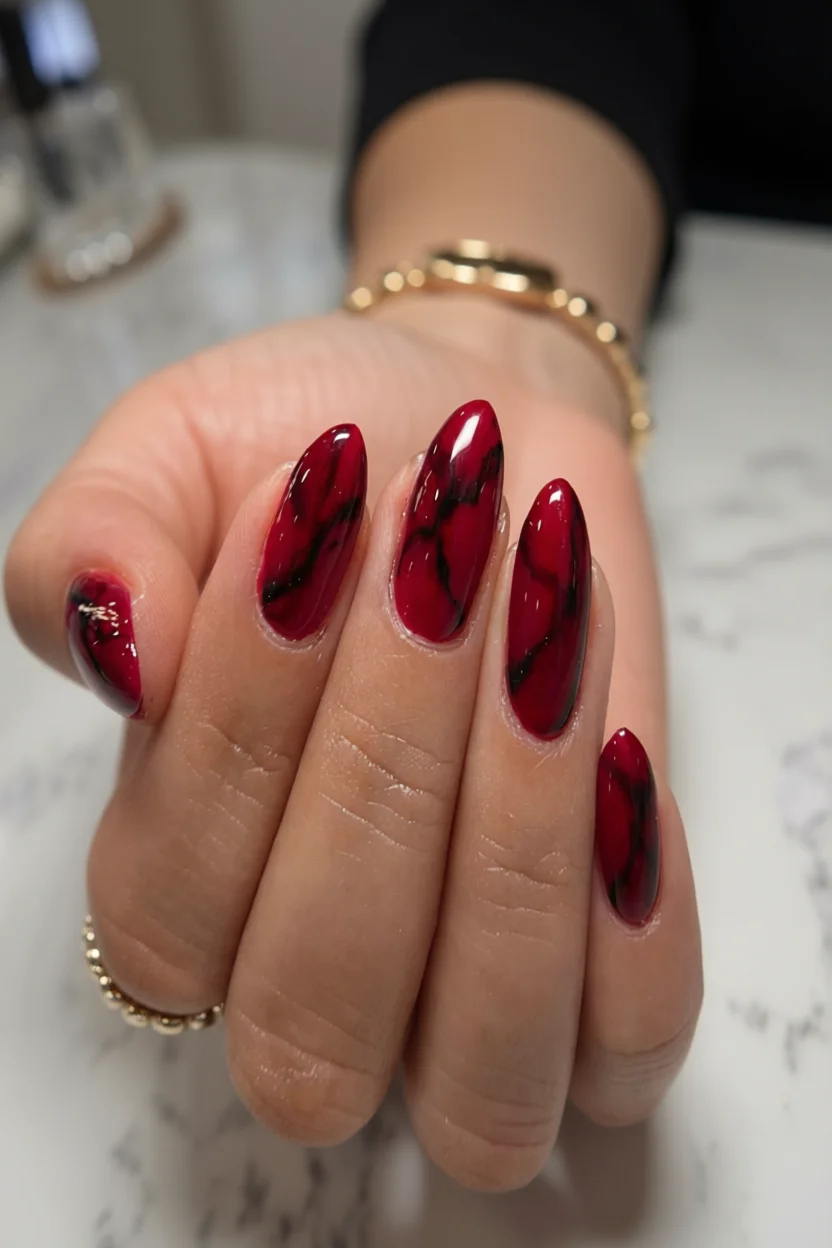 Uñas largas almendradas esmaltadas en rojo burdeos con vetas negras efecto mármol